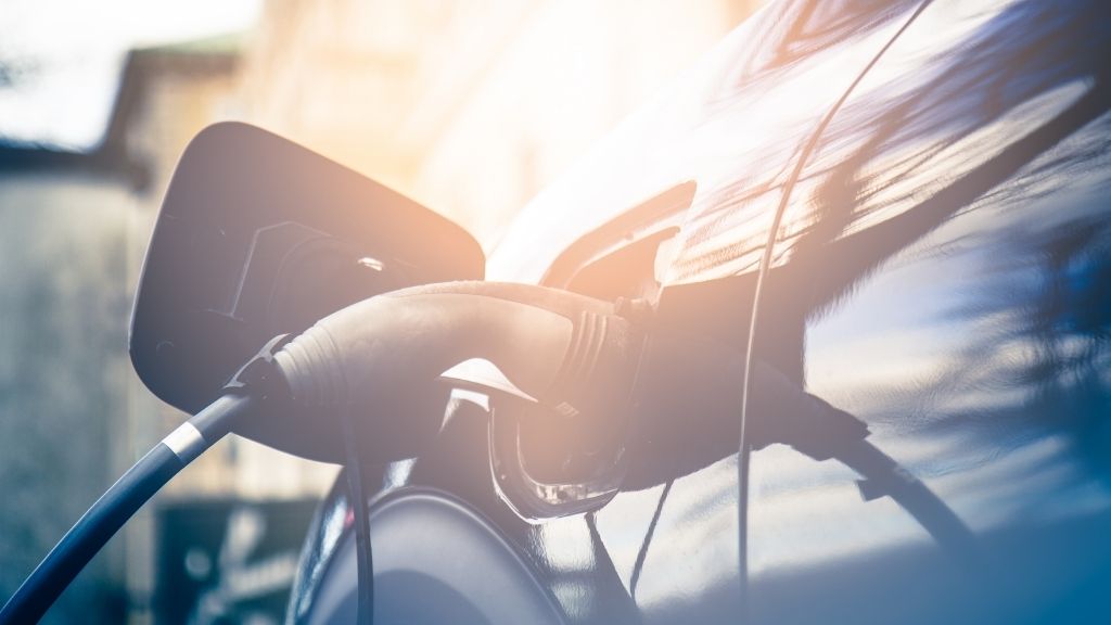 Närbild på elbil som laddas med reflekterade sol i den svarta lacken